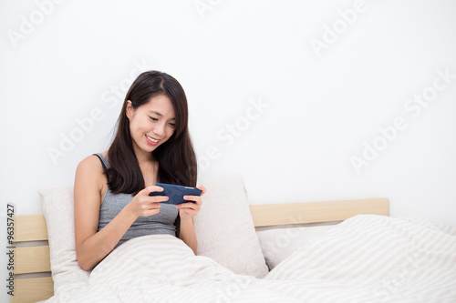 Young woman play game on smart phone in bed