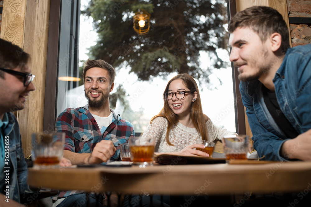 Group of friends sitting at table in cafe having fun