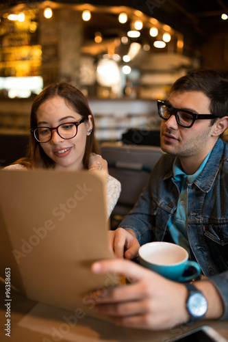 Young couple looking to the menu and choose a dish in cafe