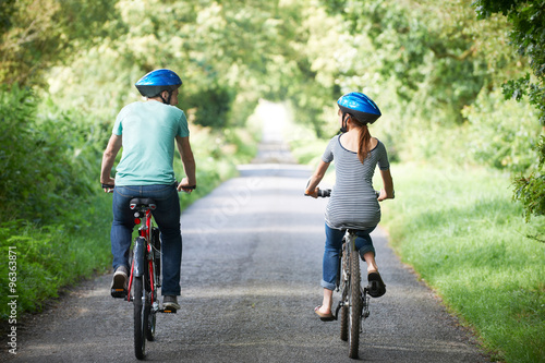Rear View Of Young Couple Cycling On Country Lane