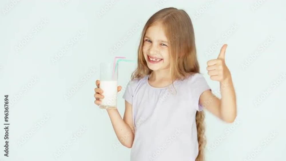 Smiling child drinking milk. Girl with beautiful blond hair on a white background. Thumb up. Ok Smiling child drinking milk. Girl with beautiful blond hair on a white background. Thumb up. Ok