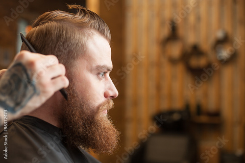 Professional young barber with a comb at beauty shop