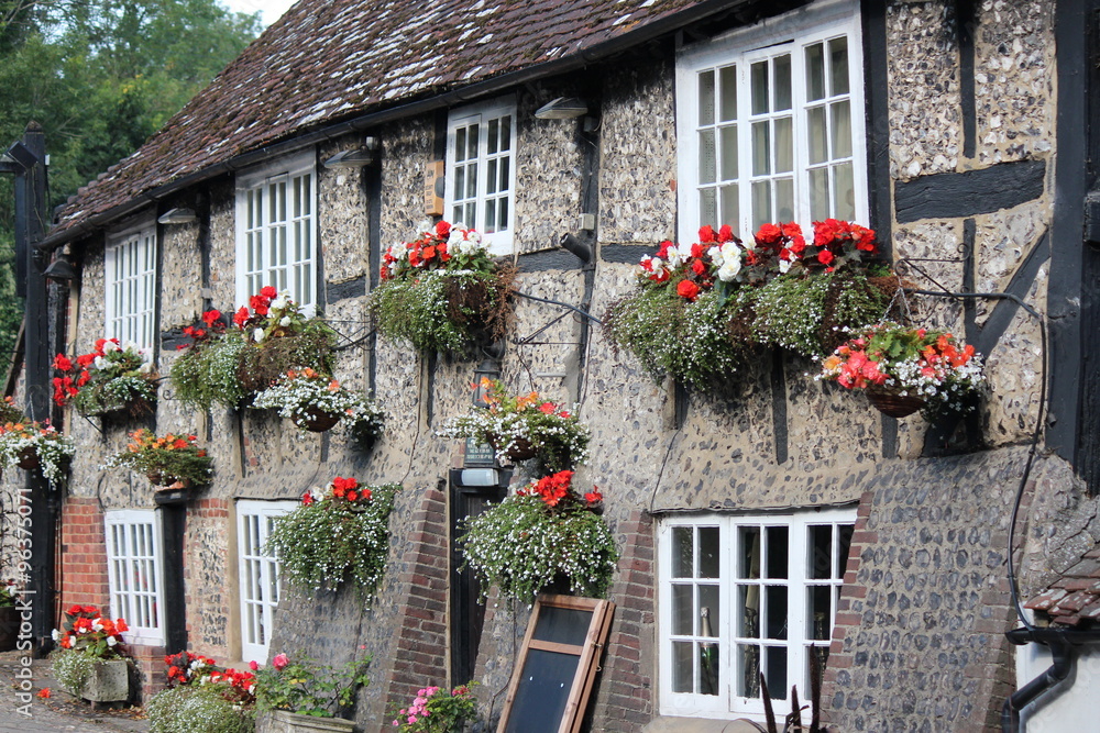 Quaint Old British Pub Decorated with Window Boxes and Hanging Baskets of Flowers in Summer.
