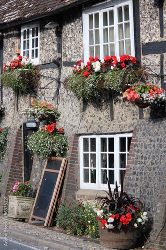 Quaint Old British Pub Decorated with Window Boxes and Hanging Baskets of Flowers in Summer.