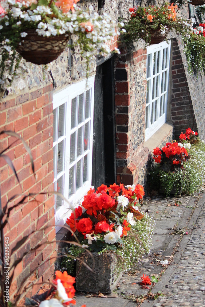 Quaint Old British Pub Decorated with Window Boxes and Hanging Baskets of Flowers in Summer.