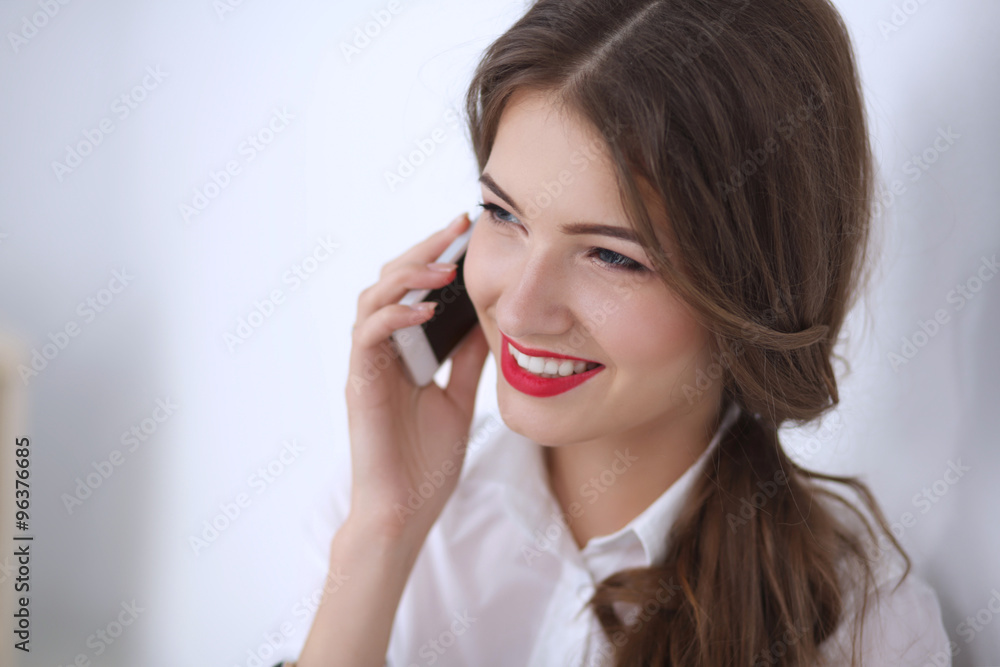 Smiling businesswoman talking on phone sitting at the office Smiling businesswoman talking on phone sitting at the office