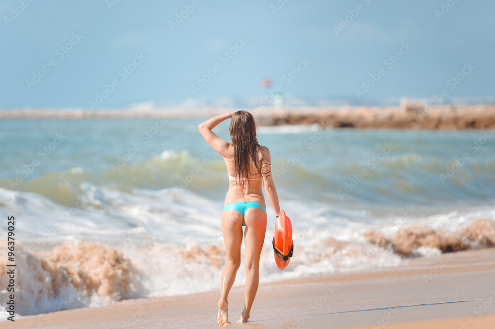 Naklejka premium Beautiful young woman with orange lifesaver equipment on sea beach