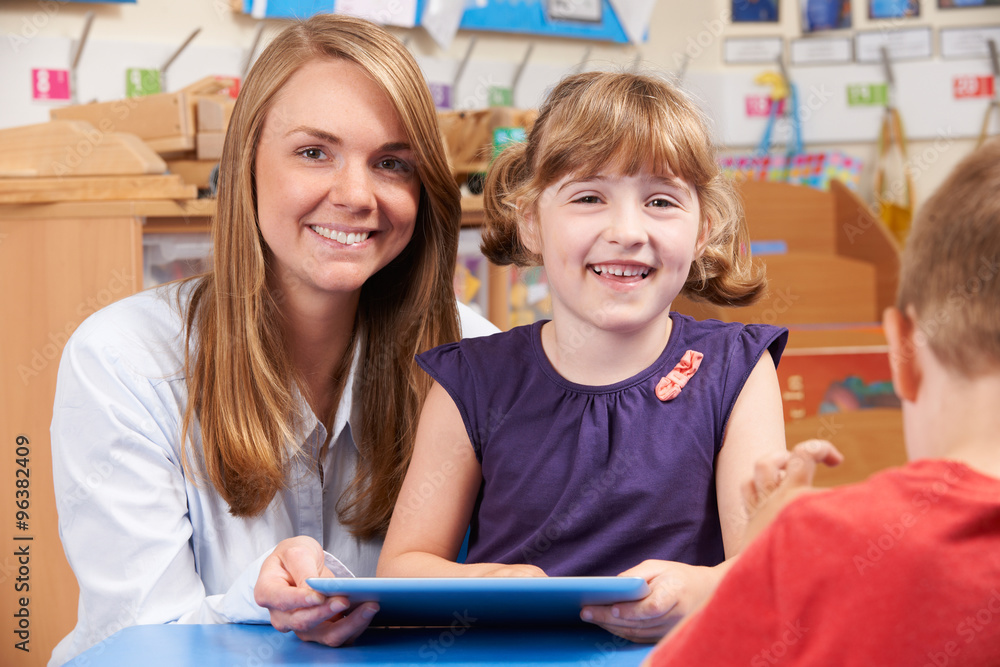 Teacher Helping Elementary Scool Pupil To Use Digital Tablet Teacher Helping Elementary Scool Pupil To Use Digital Tablet