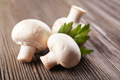 Champignon mushrooms and parsley on grey wooden background