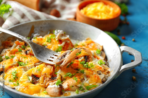 Roasted mushrooms, chicken and cheese gratin in pan, on color wooden background