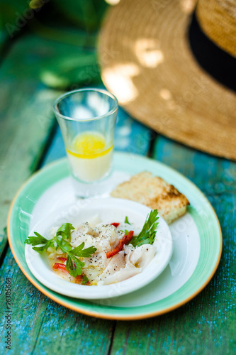 Marinated seafood on a plate with bread, on a background of straw hat