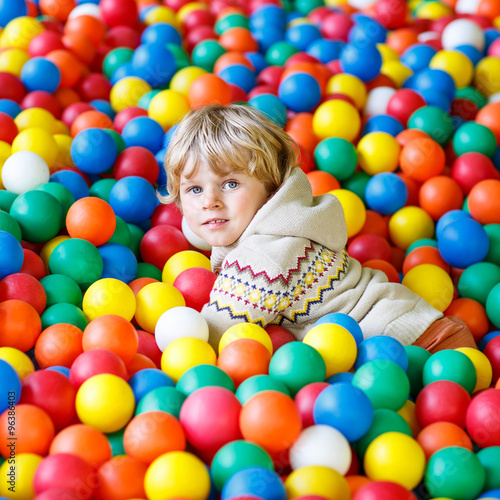 child playing at colorful plastic balls playground 