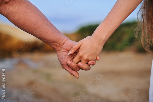 Young people are a pair of lovers in the sand and hold hands