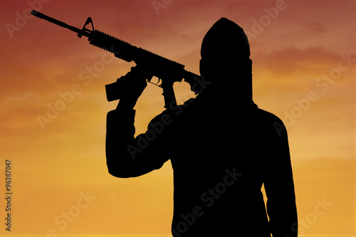 Silhouette of man standing with rifle during sunset