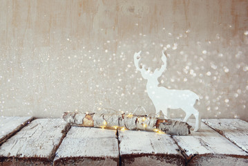 old tree log with fairy christmas lights and reindeer on wooden table.selective focus
