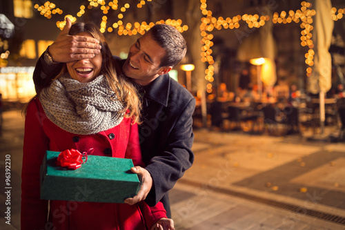 Man  keeps his girlfriend eyes covered while  she giving a gift