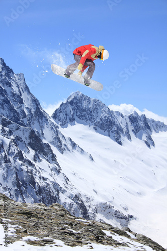 Flying snowboarder on mountains. Extreme sport