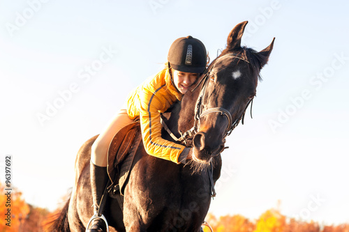 Teenage girl equestrian hugging her horse. Vibrant summertime ou