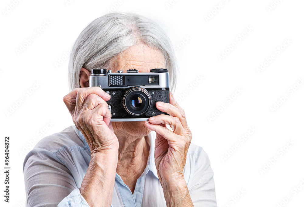 Senior woman shooting with a retro camera over white background Senior woman shooting with a retro camera over white background
