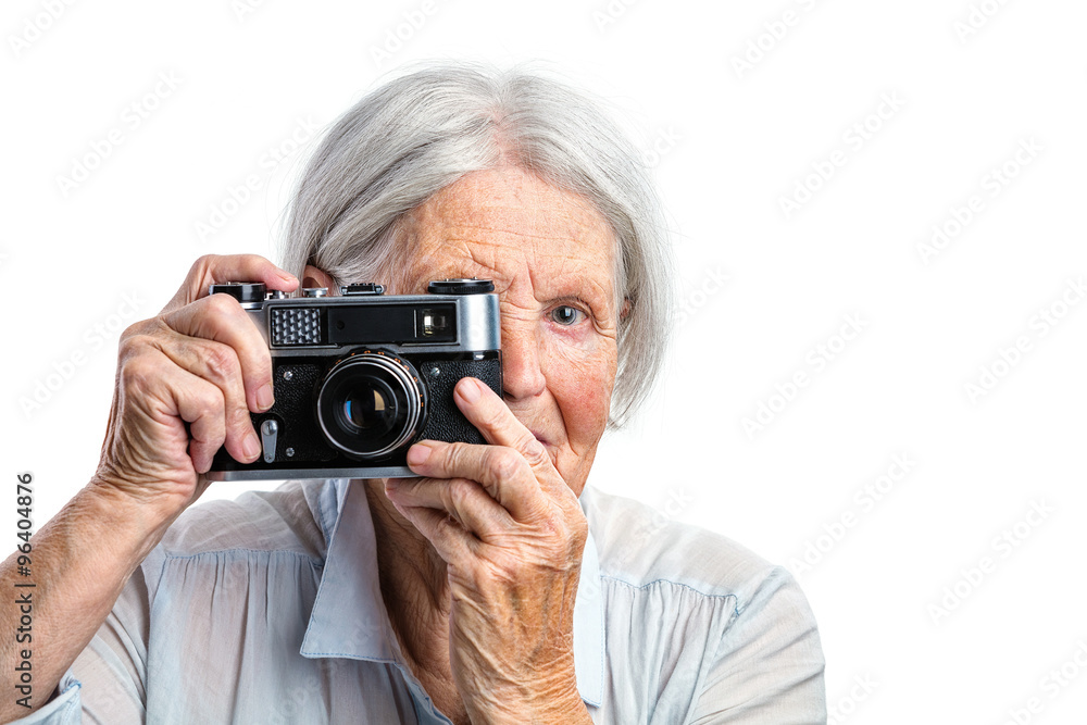 Senior woman shooting with a retro camera over white background Senior woman shooting with a retro camera over white background