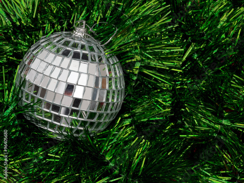Mirror ball style Christmas tree bauble on bed of green tinsel background
