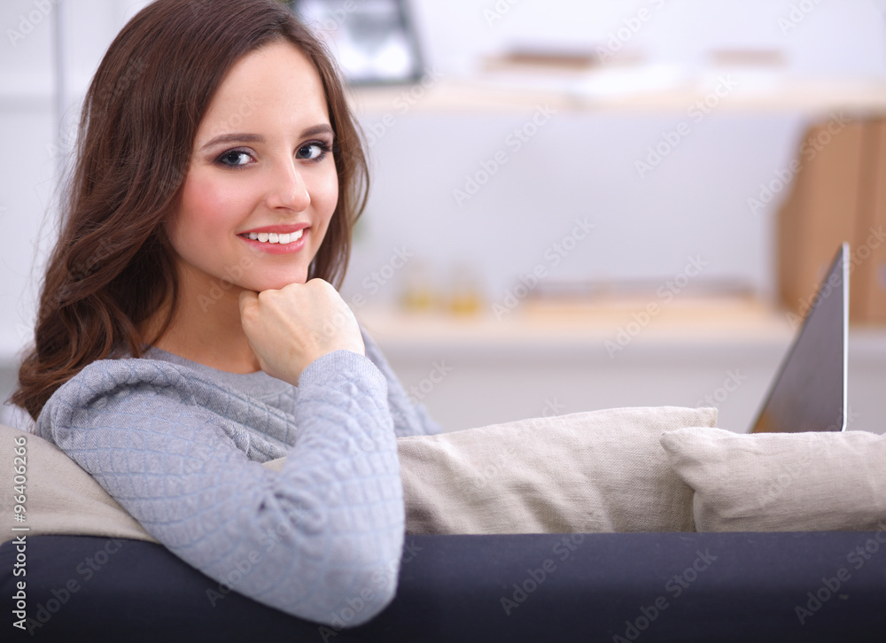 Portrait of happy young woman sitting on sofa Portrait of happy young woman sitting on sofa