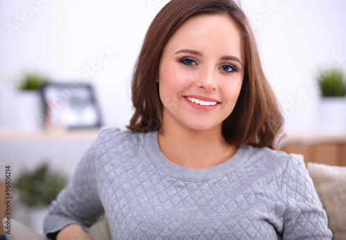 Portrait of happy young woman sitting on sofa