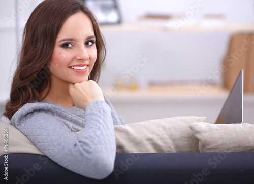 Obraz na płótnie Portrait of happy young woman sitting on sofa