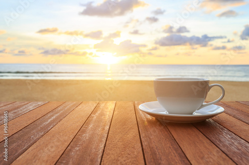 White coffee cup on wood table and view of sunset or sunrise bac
