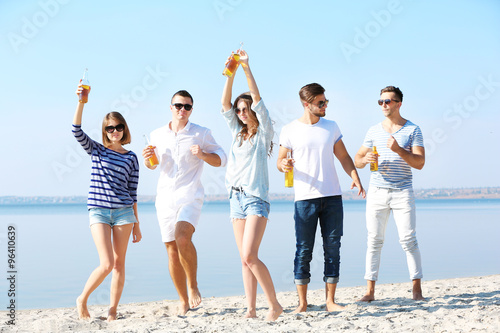 Young people with beer on the riverside