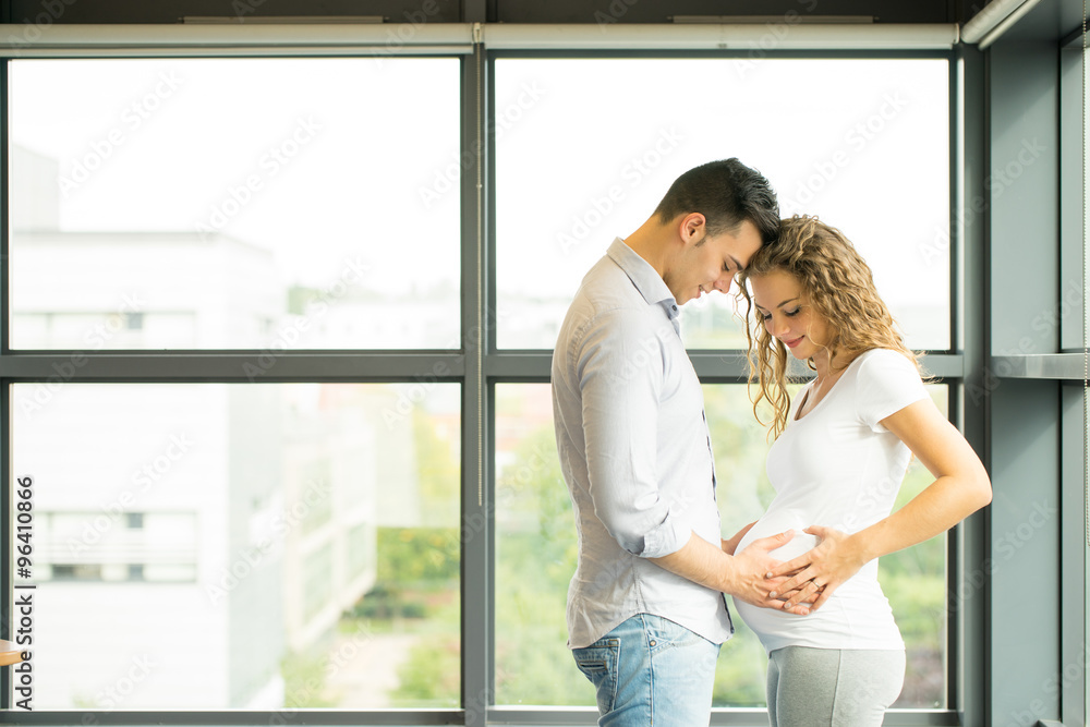 Happy and young pregnant couple in studio, white background