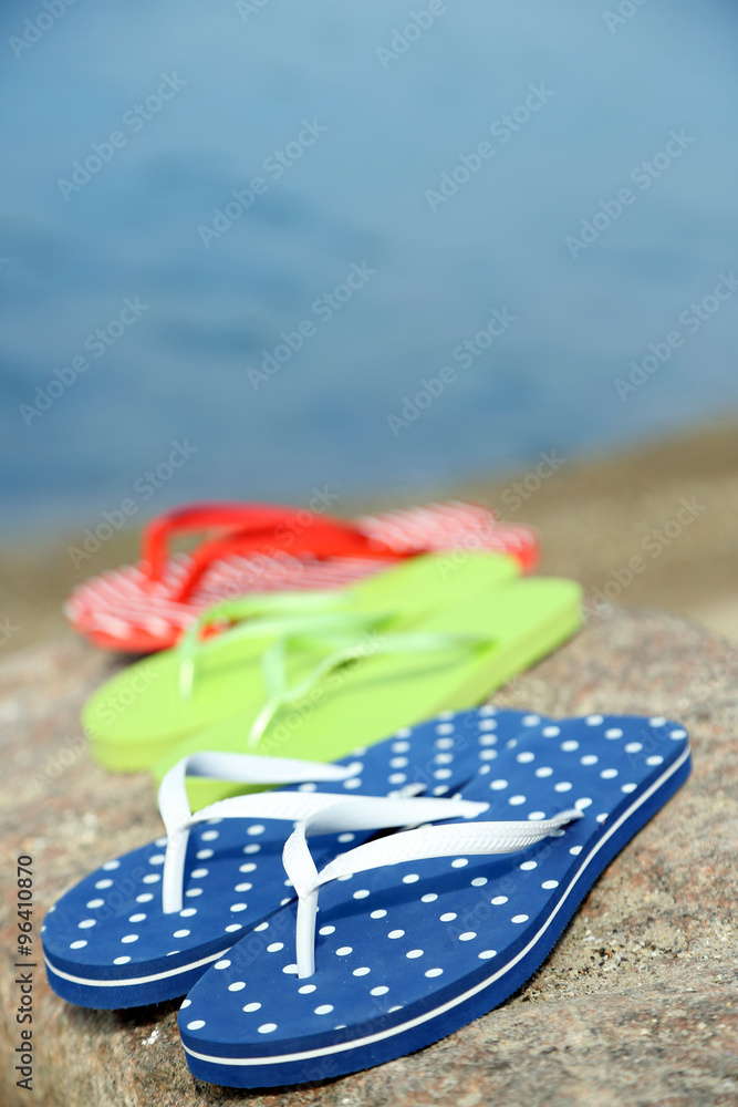 Obraz premium Bright flip-flops on stone, nature background