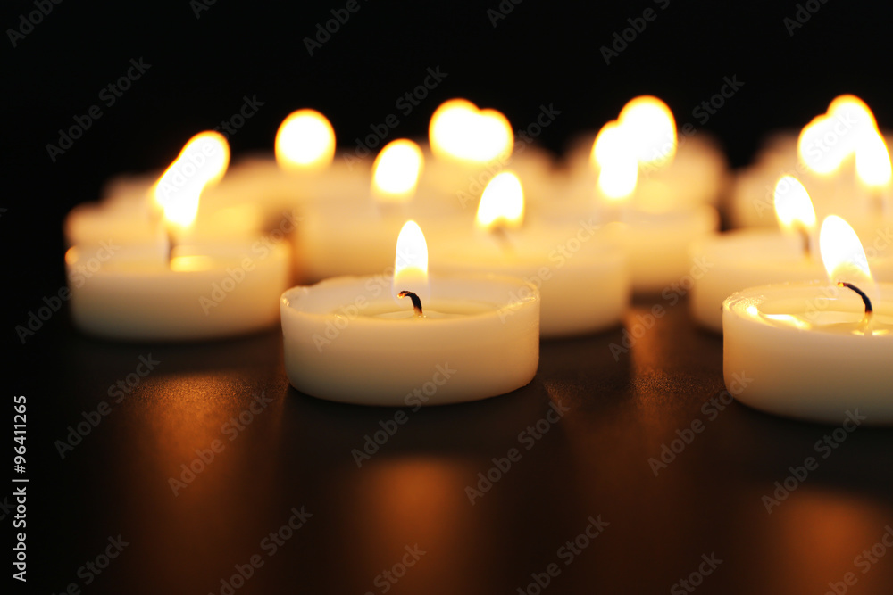 Alight candles in a row on black background, blurred Alight candles in a row on black background, blurred