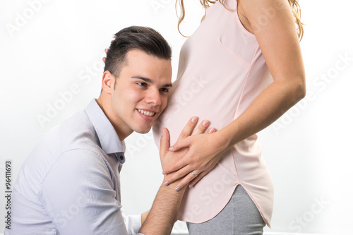 Fototapeta Naklejka Na Ścianę i Meble -  Happy and young pregnant couple in studio, white background