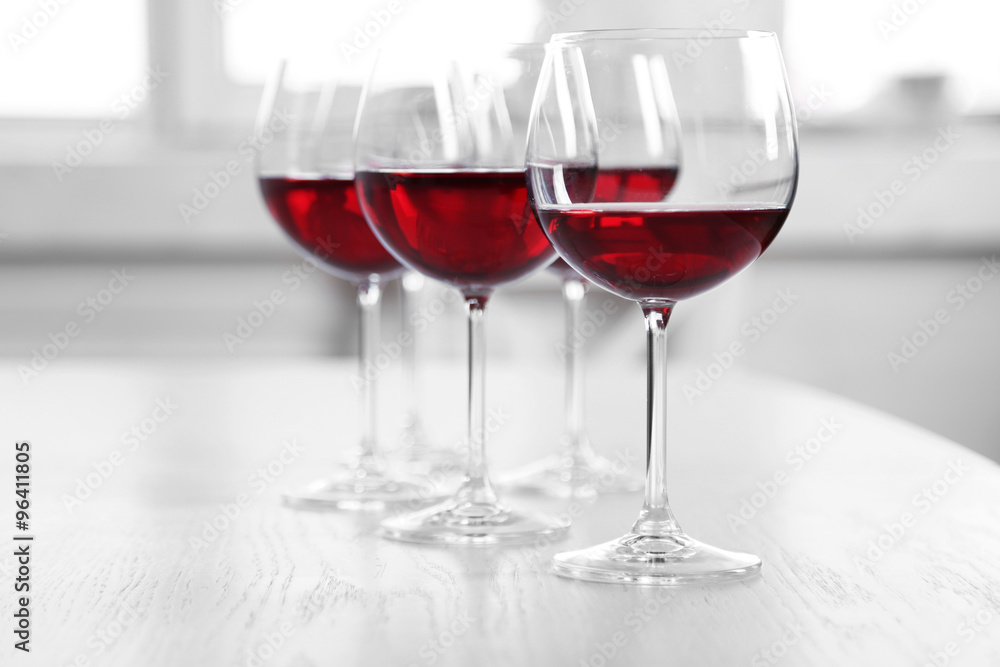 Glasses of red wine on table on bright background