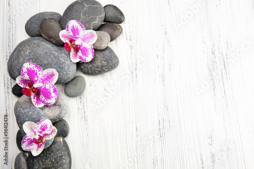 Spa stones and orchids on wooden background