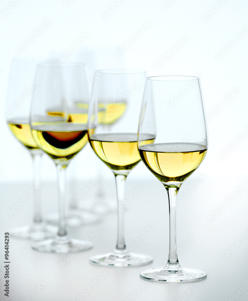 Wineglasses with white wine on wooden table on bright background