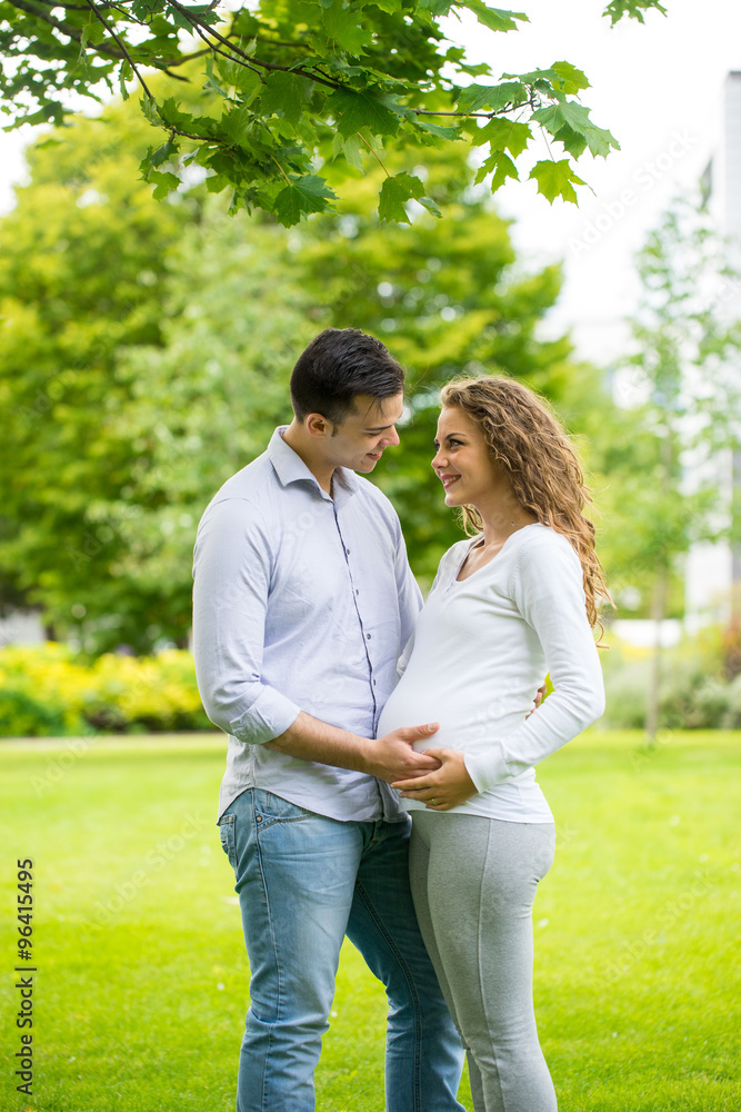 Fototapeta premium Happy and young pregnant couple in park in summer