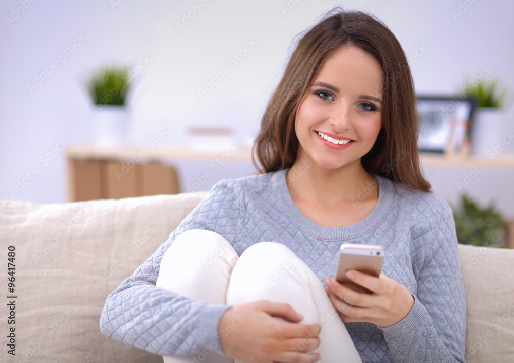 Pretty girl using her smartphone on couch at home in the living room Pretty girl using her smartphone on couch at home in the living room