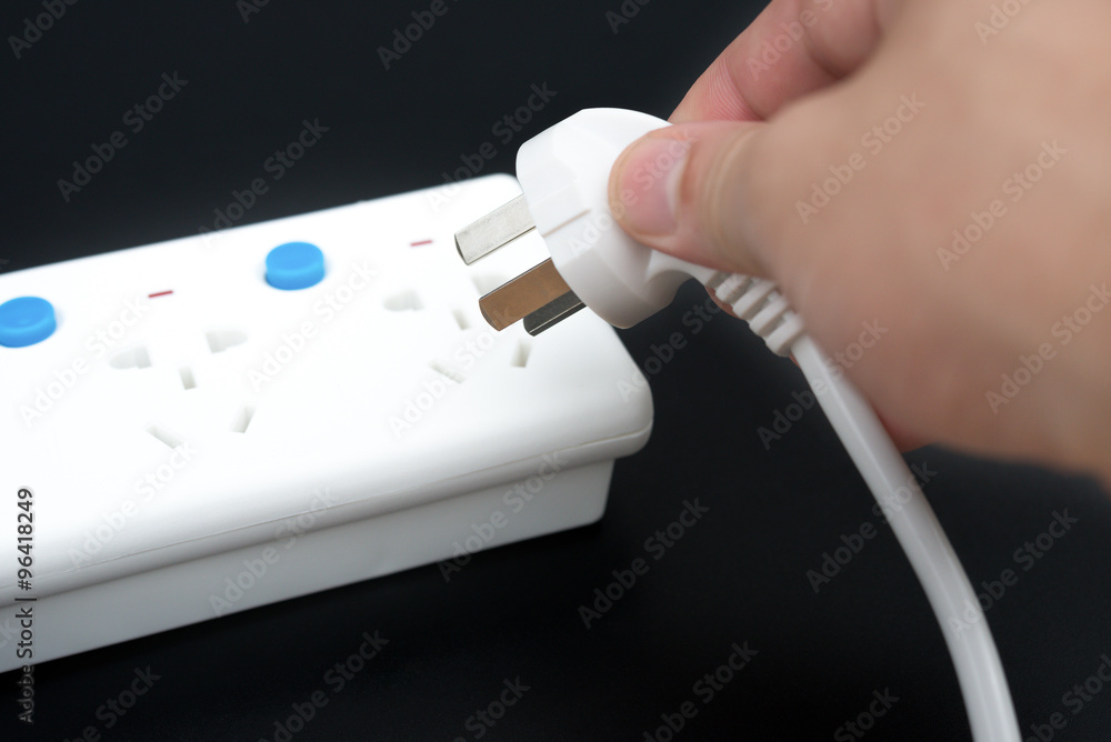 putting a plug to a multi sockets power extension on black putting a plug to a multi sockets power extension on black