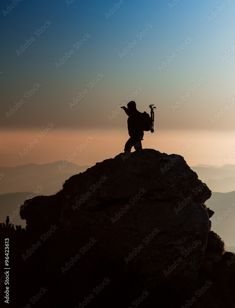 Silhouette of a photographer on the top of the mountain