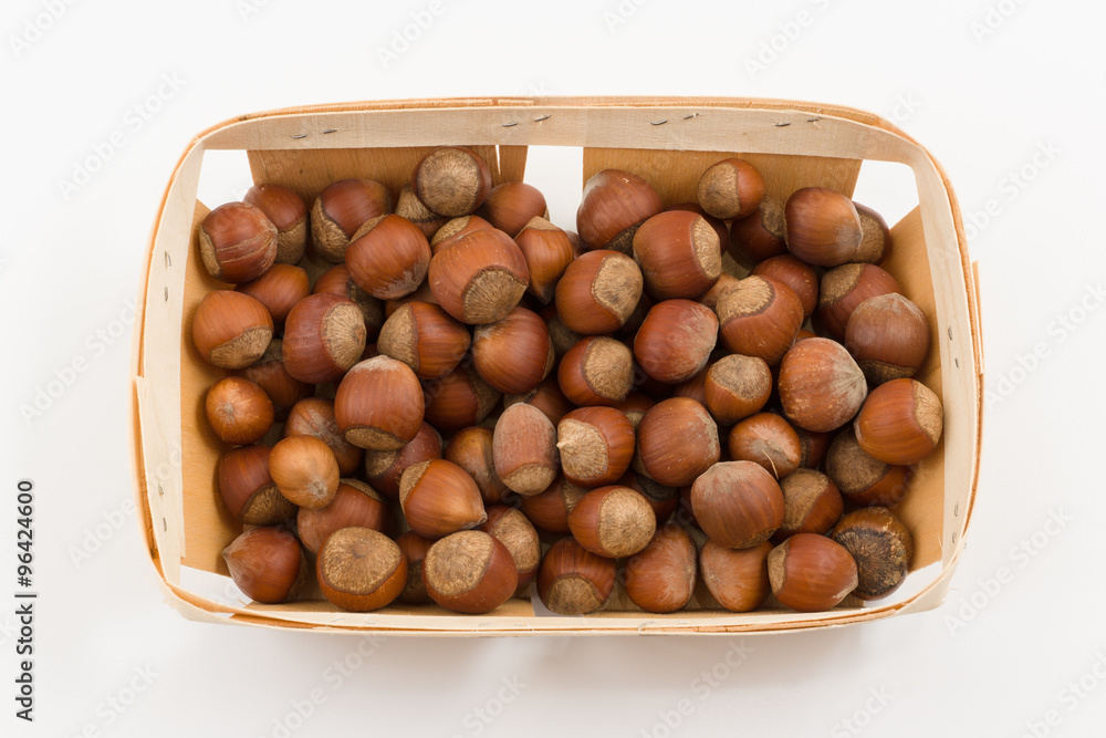 Obraz premium wooden container is filled with hazelnut on a white background