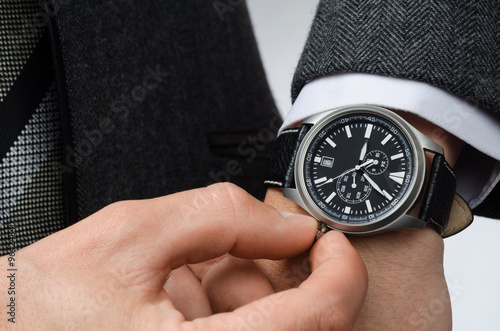 businessman adjusts the time on his wristwatch