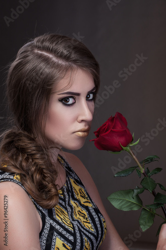 Close-up portrait, Girl with gold teeth sniffing red rose