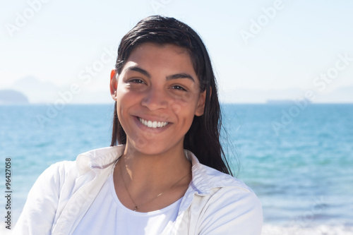 Lachende Brasilianerin mit langen Haaren am Meer