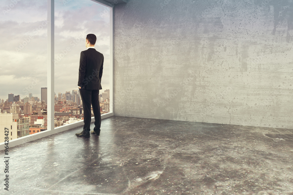 Businessman in empty loft style office with windows in floor Businessman in empty loft style office with windows in floor