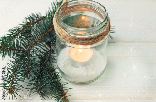 Homemade candle holder - candle in mason jar with twine and pine boughs. Soft light and focus. Toned.