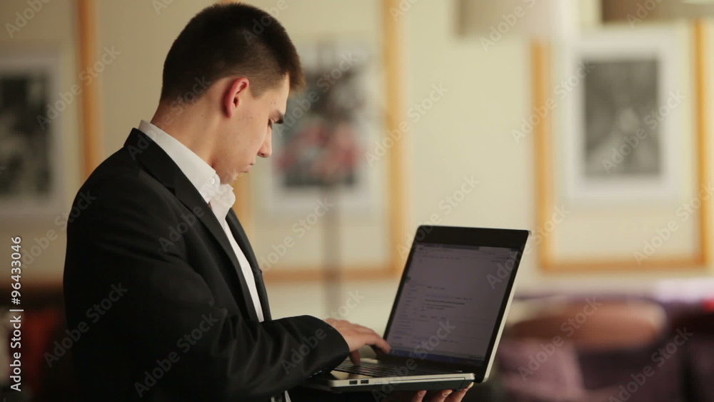 Young man with notebook typing something and smiling Young man with notebook typing something and smiling