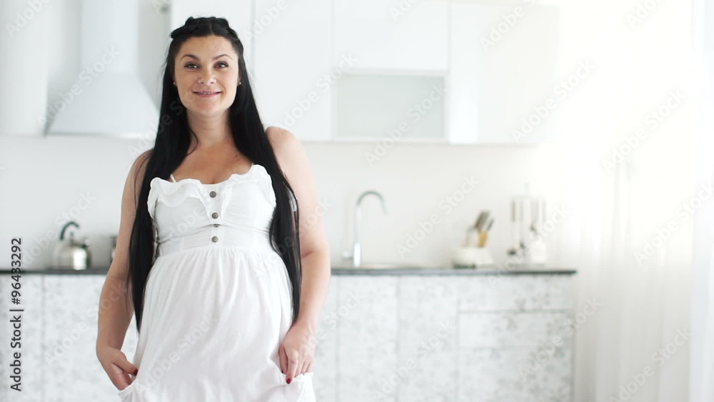 Beautiful pregnant woman stands and smiles Beautiful pregnant woman stands and smiles