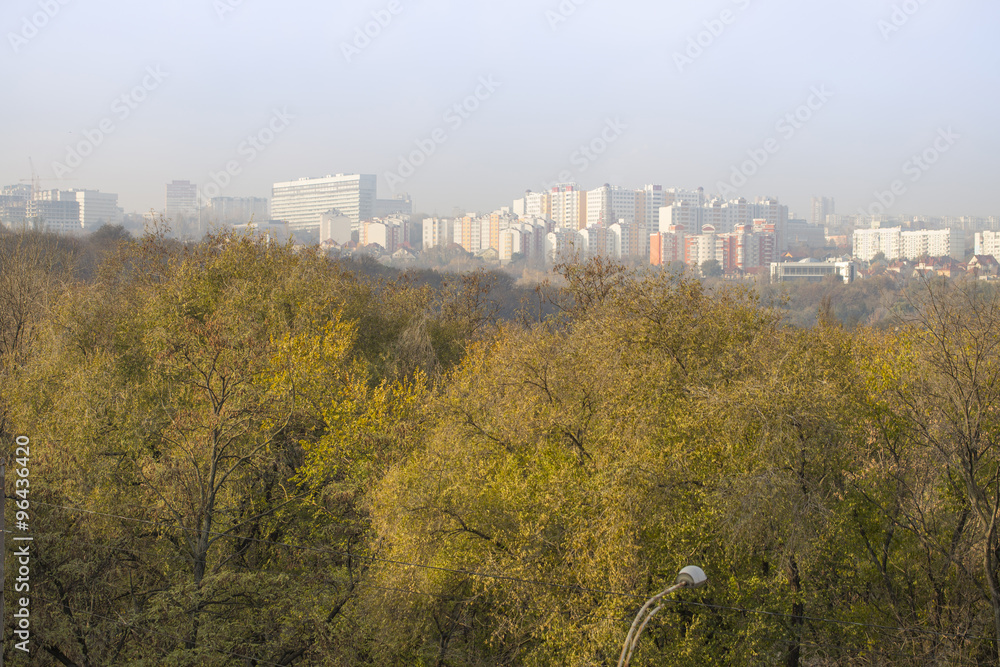 City on hill behind park scenery, autumn trees in front